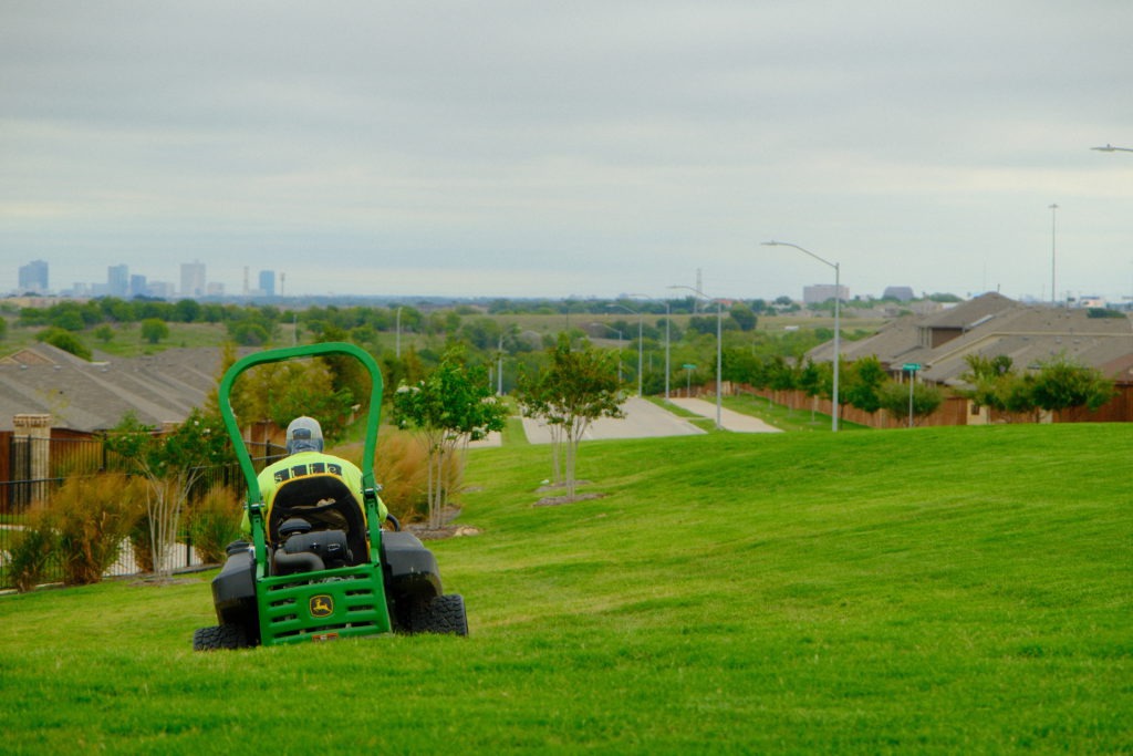 Site Landscape Development worker mowing a field near Fort Worth