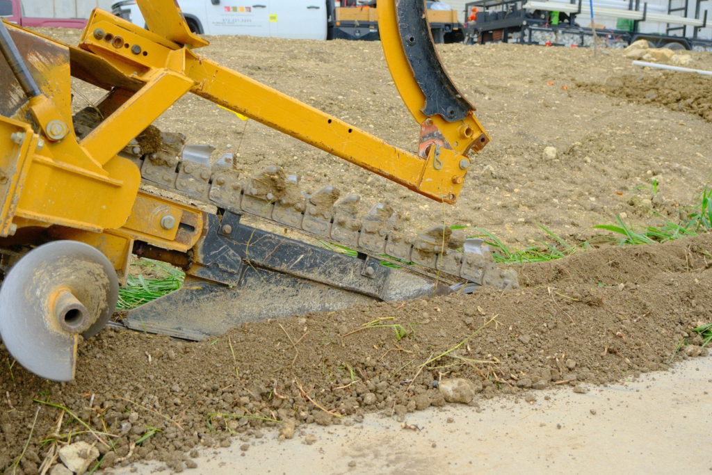 Trenching machine installing irrigation lines at commercial job site