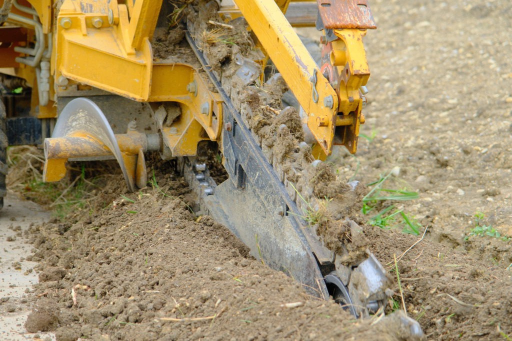 Trenching machine installing irrigation lines at commercial job site