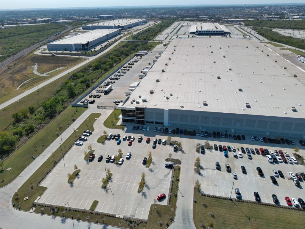 Aerial view of a large commercial distribution facility and landscaped parking areas in Fort Worth, Texas.