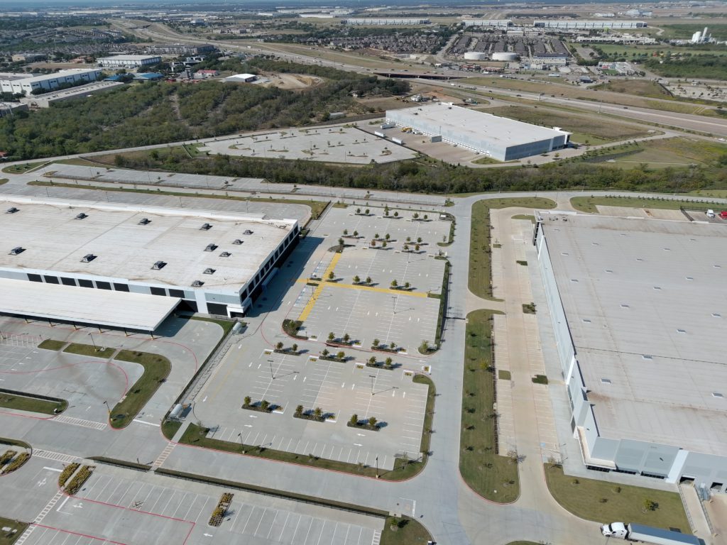 Aerial view of a large commercial distribution facility and landscaped parking areas in Fort Worth, Texas.