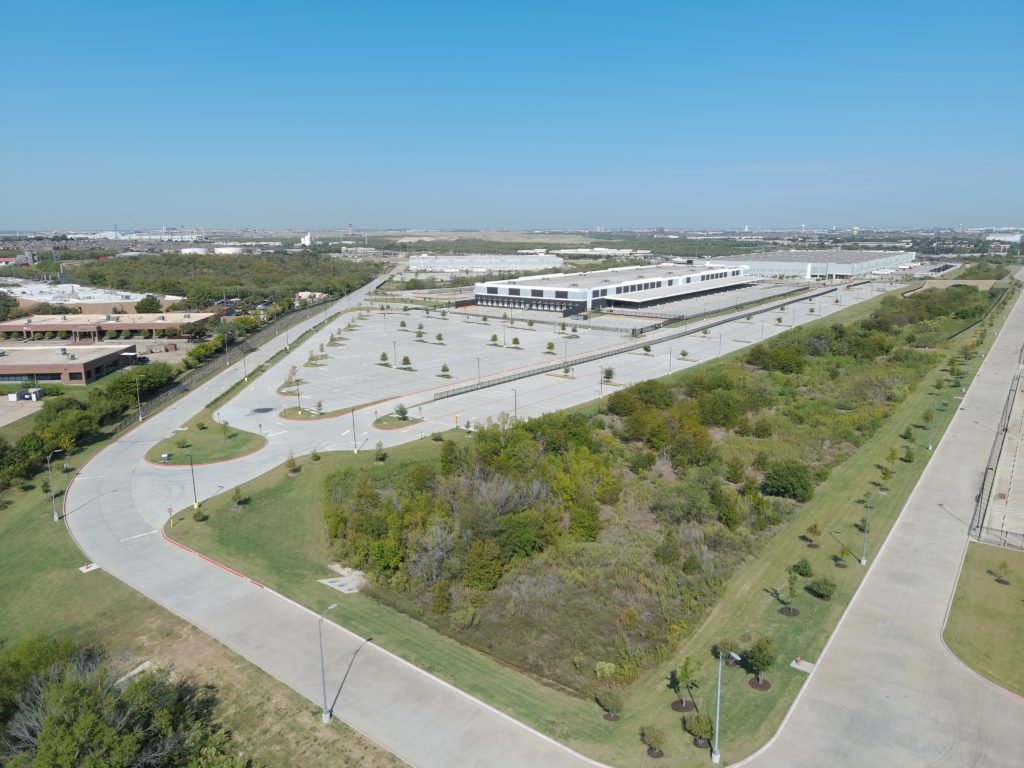 Aerial view of a large commercial distribution facility and landscaped parking areas in Fort Worth, Texas.