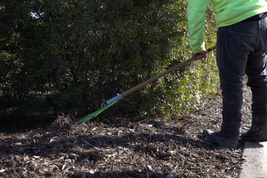 SLD crew member raking during maintenance at a commercial property.