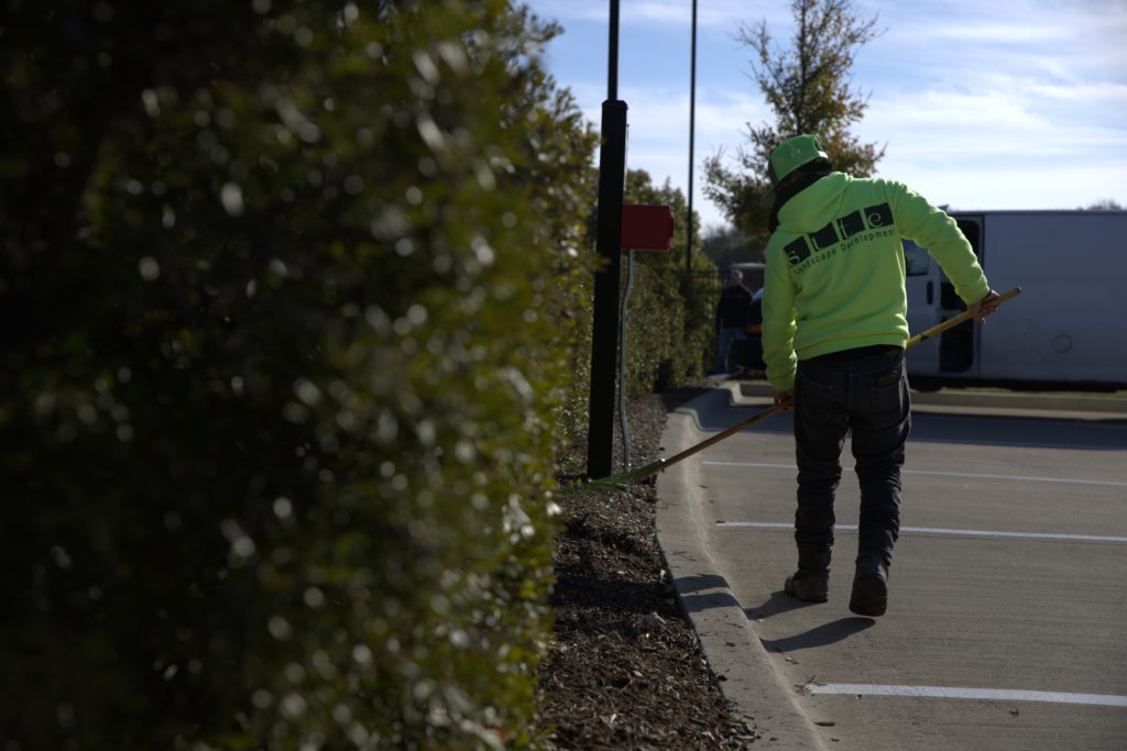 SLD crew member raking during maintenance at a commercial property.
