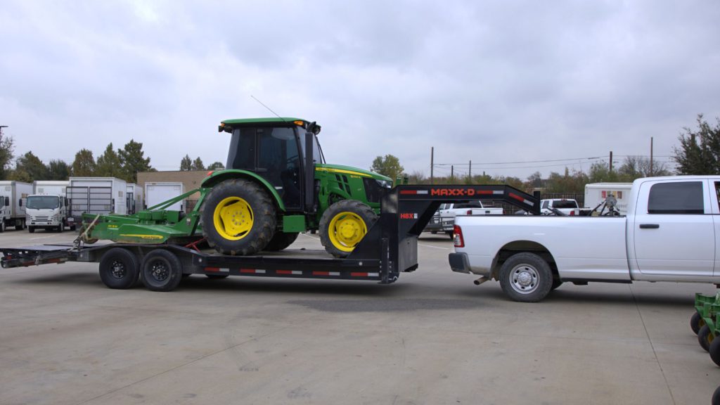 SLD work truck hauling commercial tractor on trailer for field mowing project