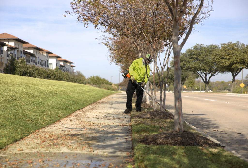 SLD crew member trimming edges with a weed eater at a commercial property in the DFW area.