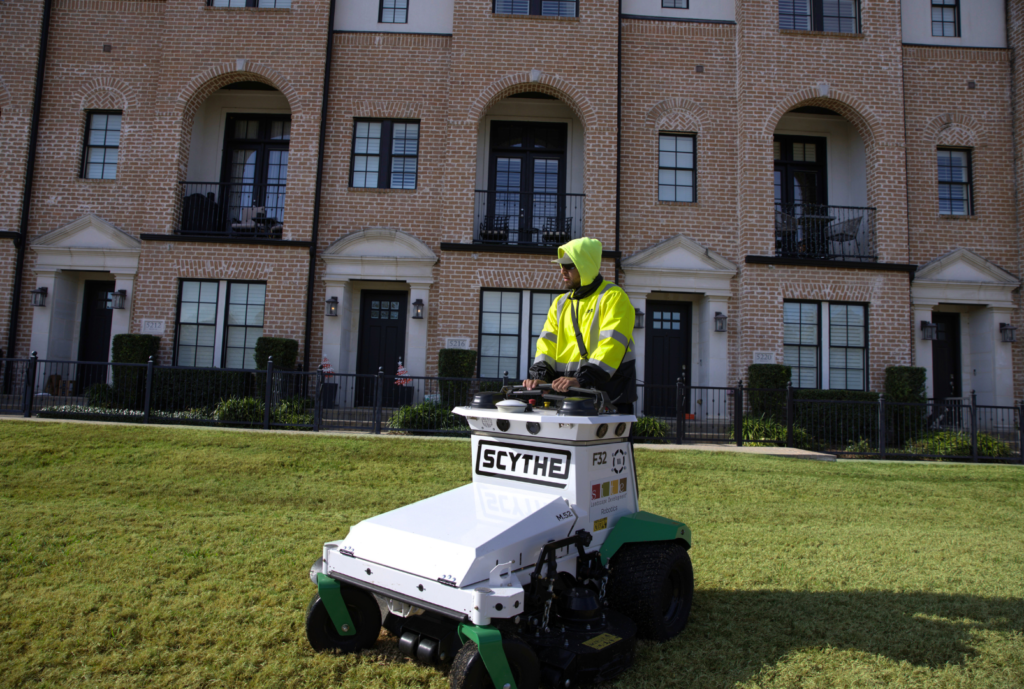 SLD crew member operating a Scythe mower at a commercial site in the DFW area.