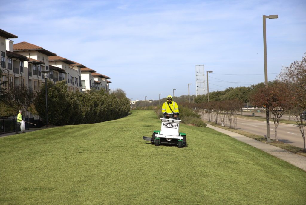 SLD crew member operating a Scythe mower at a commercial site in the DFW area.