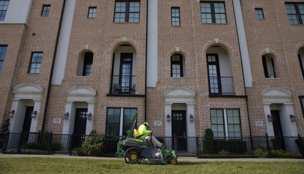 SLD crew member mowing turf with a John Deere mower at an HOA property in the DFW area.