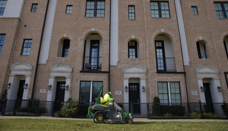 SLD crew member mowing turf with a John Deere mower at an HOA property in the DFW area.
