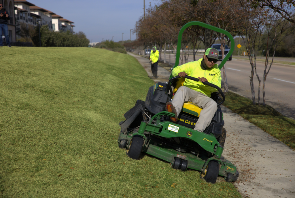 SLD crew member mowing turf with a John Deere mower at an HOA property in the DFW area.