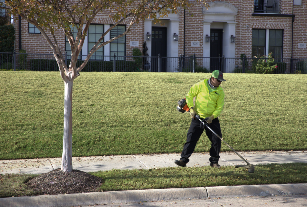 SLD crew member trimming edges with a weed eater at a commercial property in the DFW area.