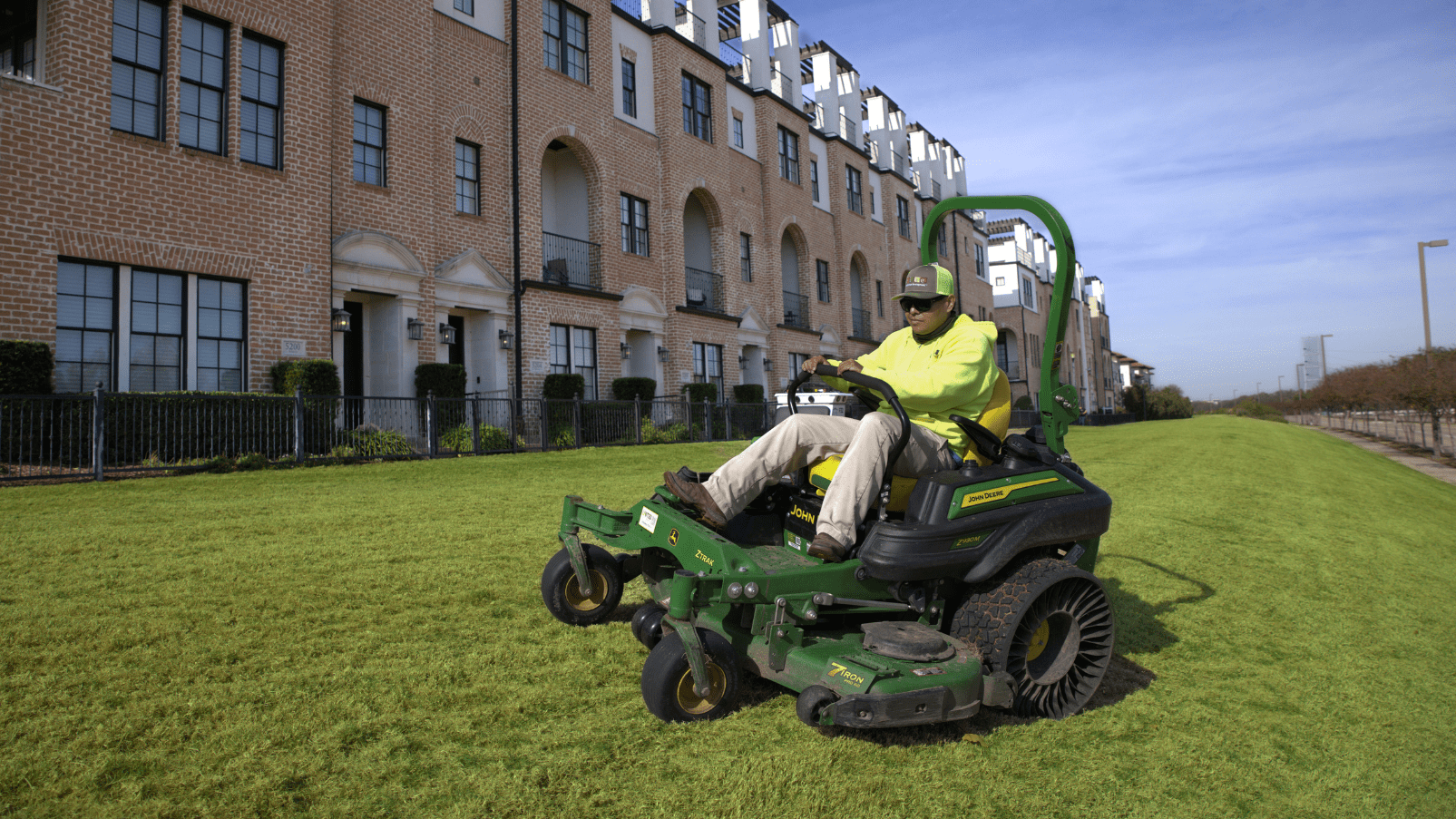 SLD crew member mowing turf with a John Deere mower at an HOA property in the DFW area.