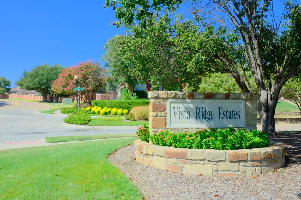 Stone entry monument for Vista Ridge Estates in Lewisville, TX, surrounded by seasonal color, shrubs and mature trees maintained by SLD.
