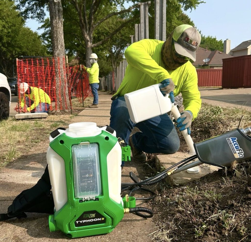 SLD crew member applying a plant growth regulator into the soil around a mature tree to help protect it during construction in DFW.